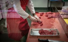 Sezione media del macellaio che taglia carne rossa in macelleria — Foto stock