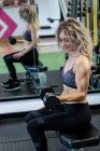 Femme soulevant haltères à la salle de gym — Photo de stock