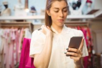 Femme utilisant un téléphone portable tout en faisant du shopping en boutique — Photo de stock