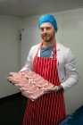 Portrait of butcher holding a tray of steaks at butchers shop — Stock Photo