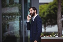 Uomo d'affari che parla al cellulare fuori dall'ufficio — Foto stock