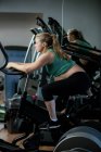 Mulher grávida trabalhando em bicicleta de exercício no ginásio — Fotografia de Stock