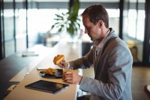 Empresário tomando café da manhã na cafetaria durante o horário comercial — Fotografia de Stock