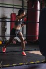 Boxeuse pratiquant la boxe avec sac de boxe dans un studio de fitness — Photo de stock