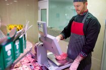 Metzger überprüft Fleischgewicht an Theke in Fleischerei — Stockfoto