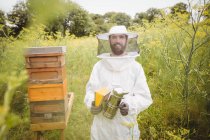 Retrato de apicultor segurando fumante de abelha no campo — Fotografia de Stock
