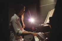 Female student playing piano in a studio — Stock Photo