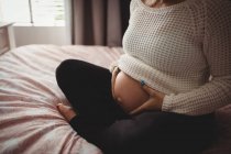 Midsection of pregnant woman relaxing in bedroom at home — Stock Photo