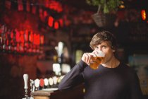 Retrato del hombre tomando un vaso de cerveza en el bar - foto de stock
