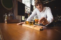 Retrato de barman segurando copo de uísque no balcão de bar no bar — Fotografia de Stock