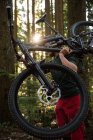 Male cyclist carrying mountain bike while walking in park — Stock Photo