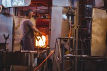 Glassblower heating glass in furnace at glassblowing factory — Stock Photo