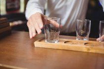 Бармен устраивает бокал пива на подносе у барной стойки в баре — стоковое фото