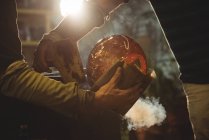 Cropped image of glassblowers shaping blown glass piece with wet cloth at glassblowing factory — Stock Photo