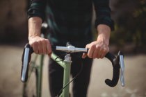 Середній розділ чоловіка, що стоїть з велосипедом на дорозі — стокове фото