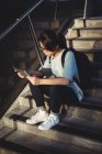 Молода жінка, сидячи на сходах і використовуючи цифровий планшетний вночі — стокове фото