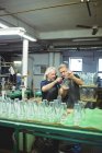 Colegas de soplador de vidrio examinando artículos de vidrio en la fábrica de soplado de vidrio - foto de stock