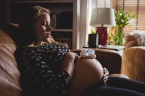 Пара дитячих шкарпеток на животі вагітної жінки в домашніх умовах — стокове фото