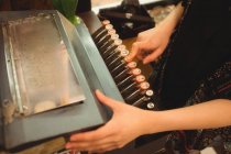 Seção média de mulher usando máquina de escrever no balcão na loja — Fotografia de Stock