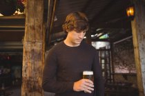 Uomo che tiene un bicchiere di birra al bar — Foto stock