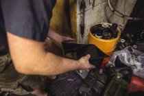 Mechanic pouring oil into can at workshop — Stock Photo