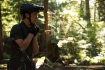 Atlético masculino usando capacete de bicicleta na floresta — Fotografia de Stock