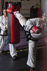 Sportlerin und Sportler beim Karate mit Boxsack im Studio — Stockfoto
