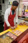 Macellaio che taglia pollo sul banco da lavoro in macelleria — Foto stock
