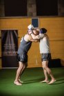 Vista lateral de boxers tailandeses praticando boxe no estúdio de fitness — Fotografia de Stock