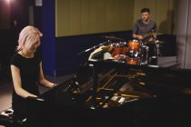 Студенти-чоловіки грають на фортепіано та барабанах у студії — стокове фото