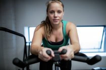 Porträt einer schwangeren Frau, die im Fitnessstudio auf dem Heimtrainer trainiert — Stockfoto