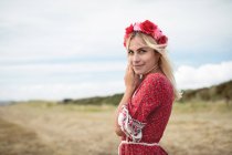 Весела блондинка в квітковій тіарі, що стоїть на полі — стокове фото