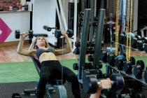Beautiful woman lifting dumbbells at gym — Stock Photo