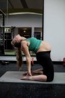 Femme enceinte effectuant des exercices d'étirement sur tapis d'exercice dans la salle de gym — Photo de stock