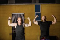 Retrato de dos boxeadores tailandeses mostrando músculos en un gimnasio - foto de stock