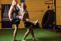 Vista lateral de dois boxers de chute praticando boxe no ginásio — Fotografia de Stock