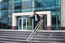 Бизнесмен разговаривает по мобильному телефону, когда идет по лестнице — стоковое фото