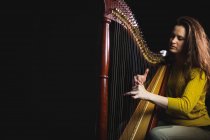 Aufmerksame Frau spielt Harfe in Musikschule — Stockfoto
