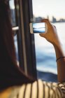 Вид ззаду жінки, що фотографує міський пейзаж на мобільному телефоні — стокове фото