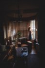Donna che guarda attraverso la finestra in soggiorno a casa — Foto stock