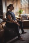 Pregnant woman performing yoga on fitness ball in living room at home — Stock Photo