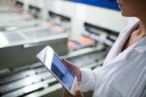 Обрізане зображення жіночого персоналу з використанням цифрового планшета поруч з виробничою лінією на яєчному заводі — стокове фото