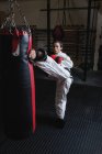 Esportista praticando karatê com saco de perfuração no estúdio de fitness — Fotografia de Stock