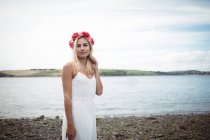 Unbekümmerte blonde Frau in weißem Kleid und Blume-Diadem am Fluss — Stockfoto