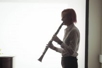 Beautiful woman playing a clarinet in music school — Stock Photo