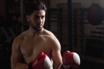 Боксер без рубашки практикующий бокс в фитнес-студии — стоковое фото