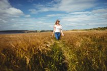 Жінка проходить через пшеничне поле в сонячний день — стокове фото