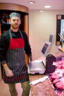 Portrait of butcher standing at counter in butchers shop — Stock Photo