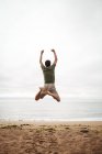 Visão traseira do homem pulando na praia — Fotografia de Stock