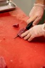 Mani di macellaio che tagliano carne rossa in macelleria — Foto stock